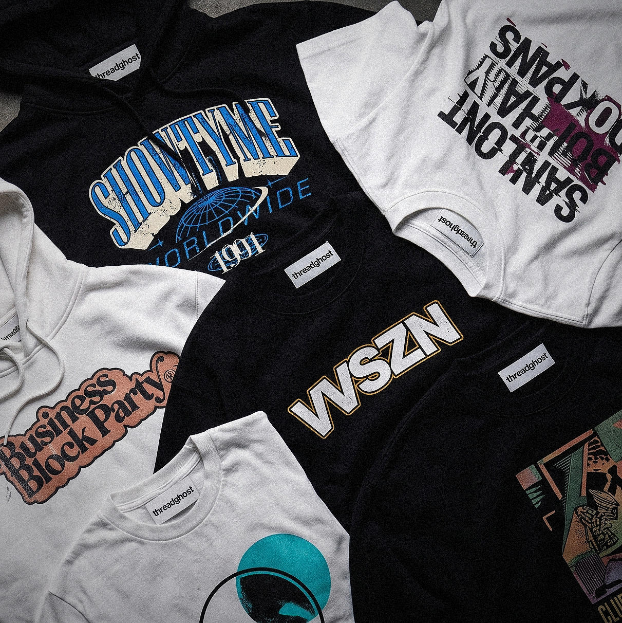 A flatlay of DTG-printed tees and hoodies in black and white