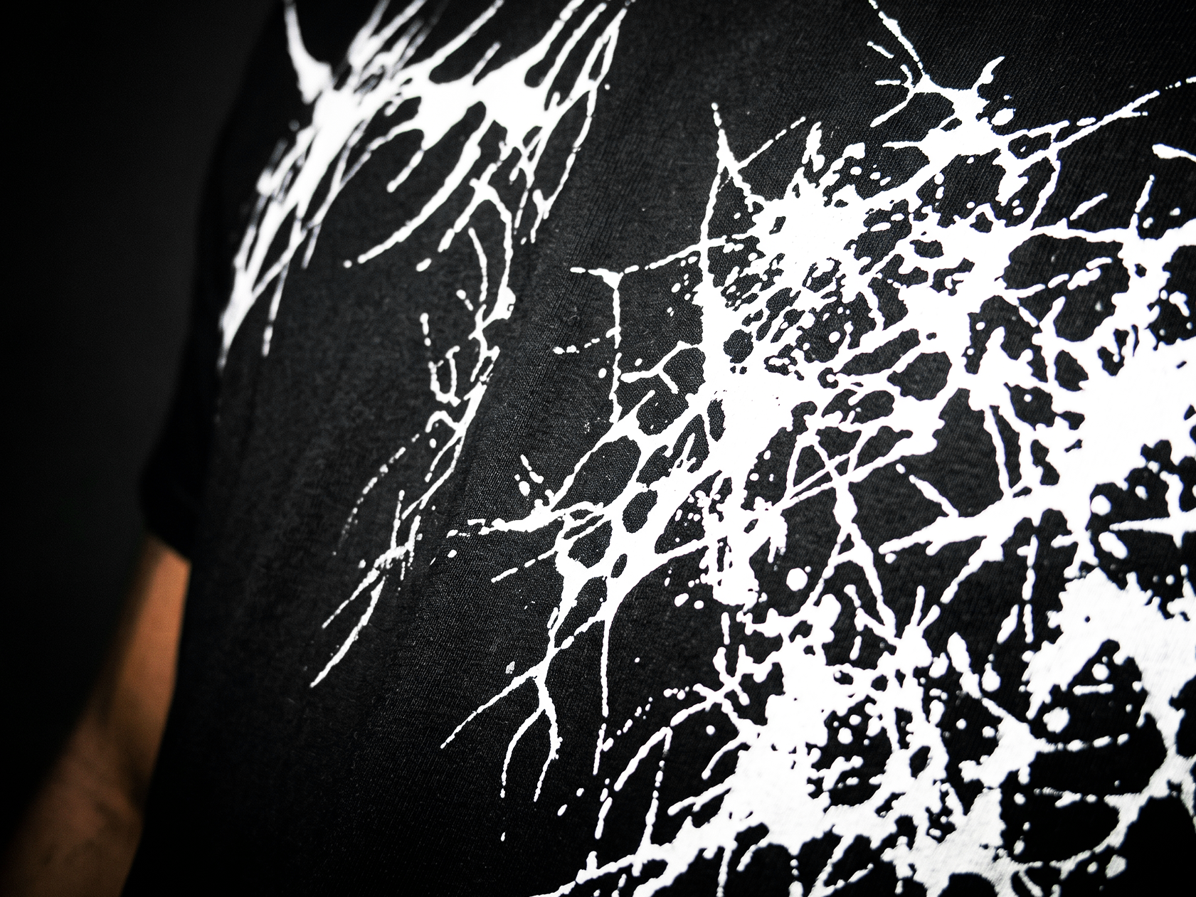 A high-contrast screen printed splatter graphic across a black garment