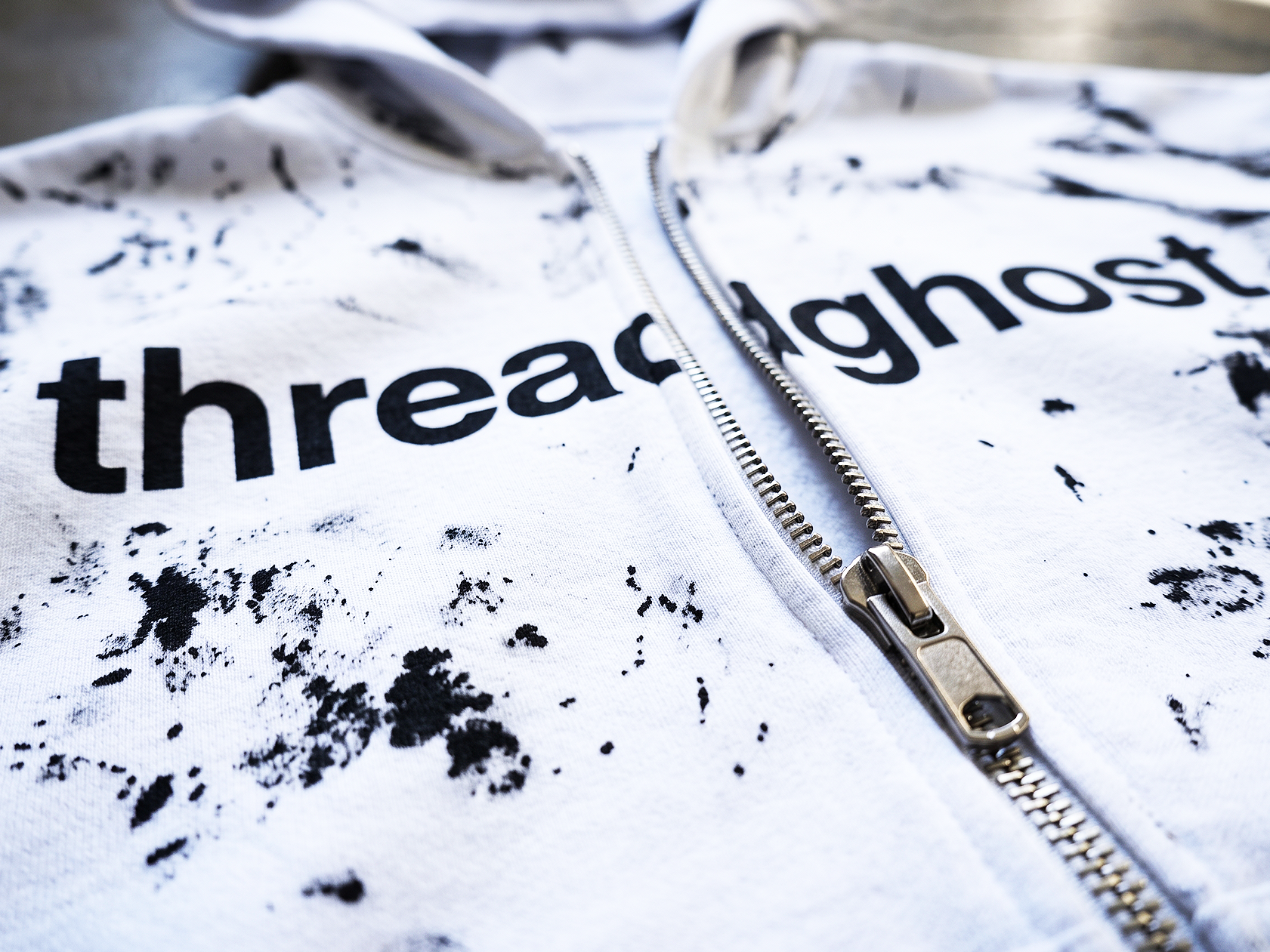 A white zip hoodie with a black splattered dye finish