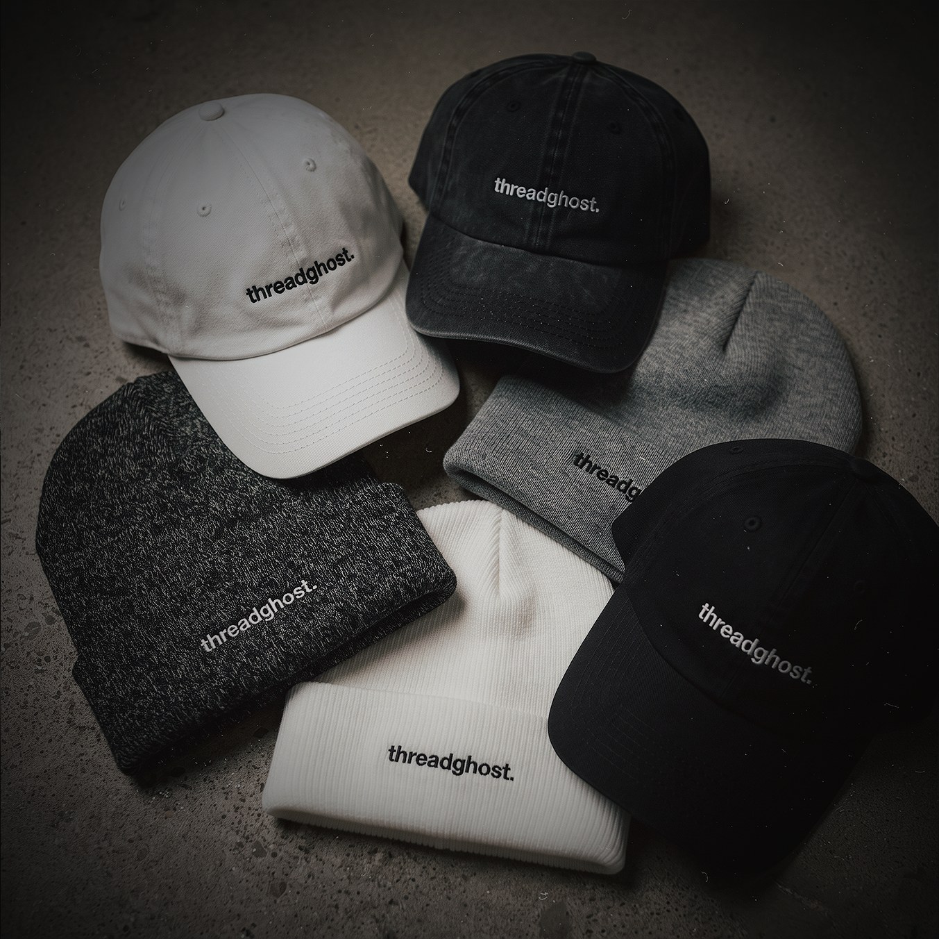 Threadghost caps and beanies laid out on concrete