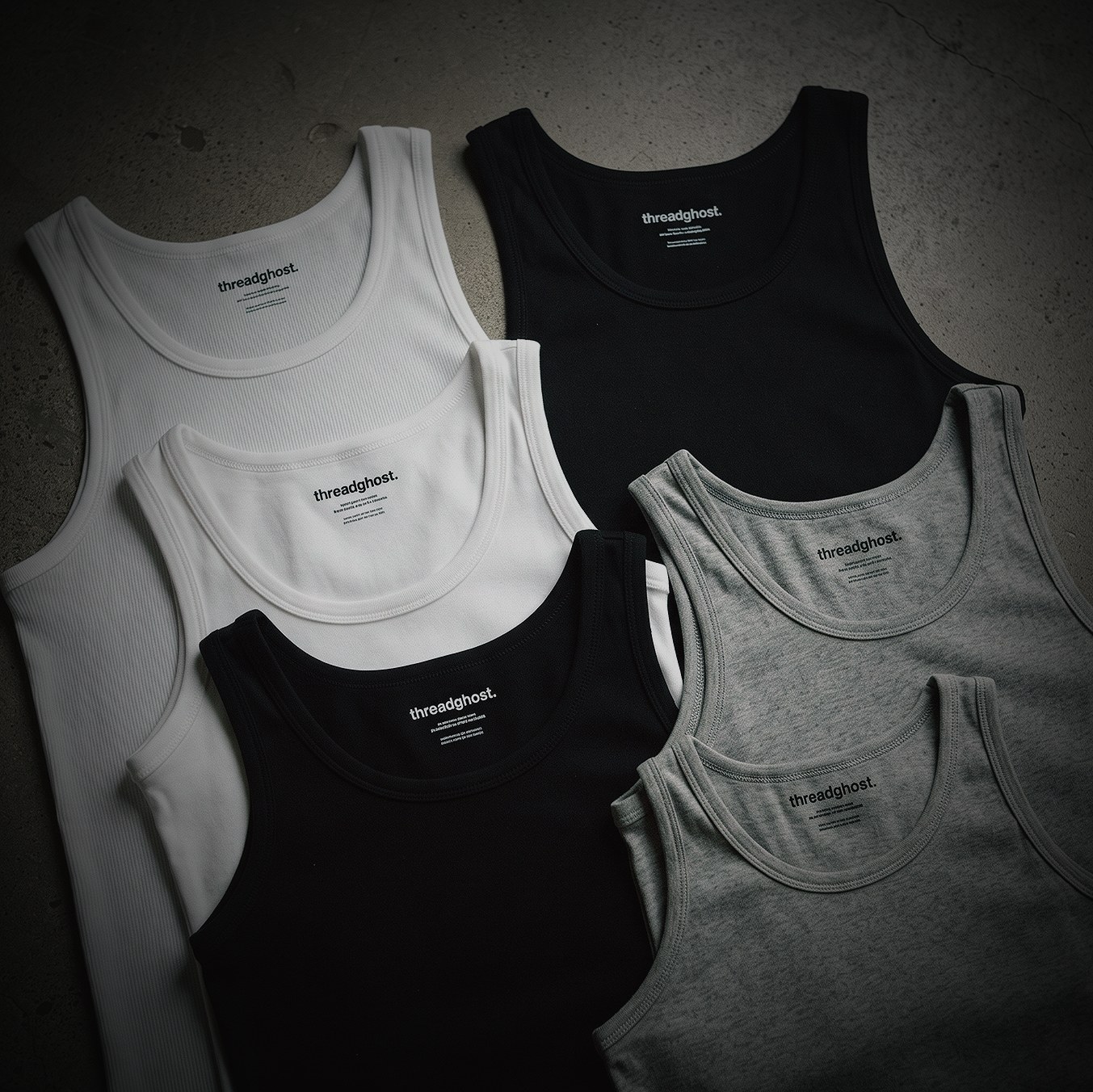 Black, white and grey threadghost tanks folded on concrete